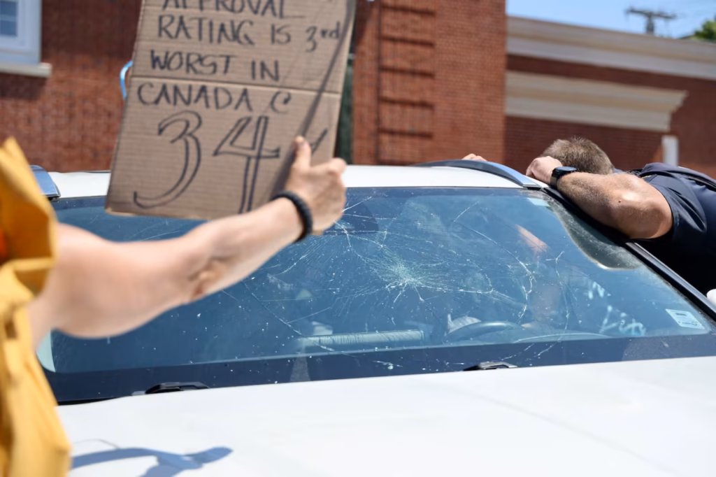 Nova Scotia Premier Tim Houston’S Car Surrounded And Windshield Smashed — Police Escort Him From The Scene Tim Houston car surrounded by protesters in Wolfville Nova Scotia July 15 2026 after speech at Acadia University Annapolis Valley Chamber of Commerce