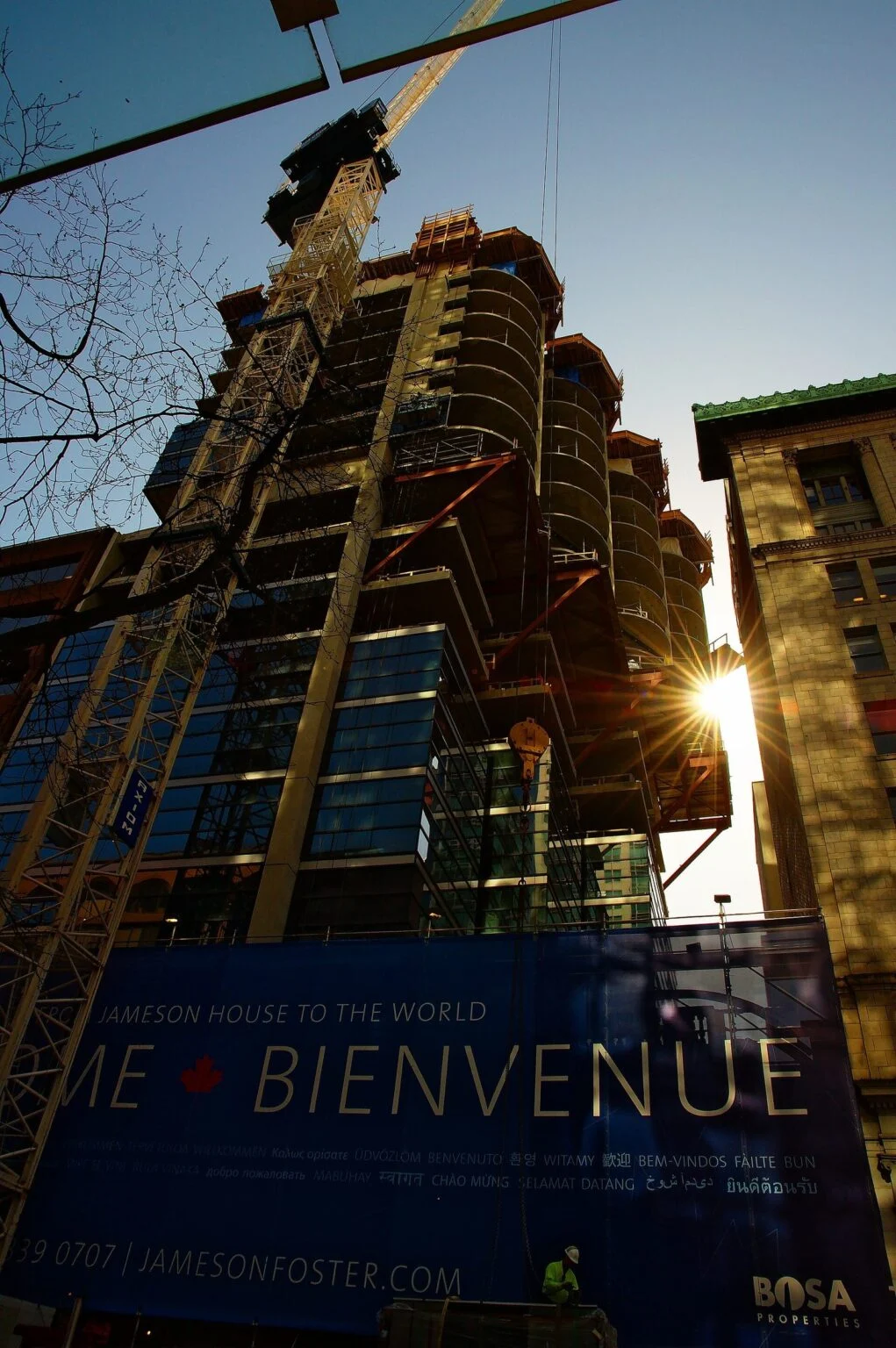 B.c. Ndp Pledges Unsold Condo Tax To Crack Down On Empty Units — Election 2026 Housing Plan A condo tower under construction with a tower crane in downtown Vancouver, at the heart of the Unsold Condo Tax debate