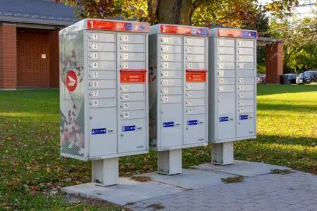 Canada Post Door-To-Door Delivery Cuts 2026 — Regina And Saskatoon Lose Home Mail Delivery Three Canada Post community mailboxes on a sunny street, central to the Canada Post Door-to-Door Delivery cuts coming to Regina and Saskatoon