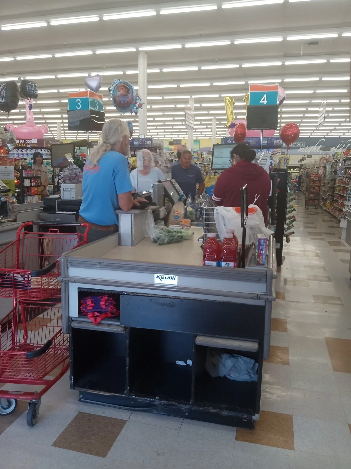 Competition Bureau Empire Grocery Deal 2026 — Sobeys Owner Agrees To Scrap Anti-Competition Property Controls 2 Shoppers at a grocery checkout counter, where Canadians feel the prices the Competition Bureau Empire grocery deal aims to address
