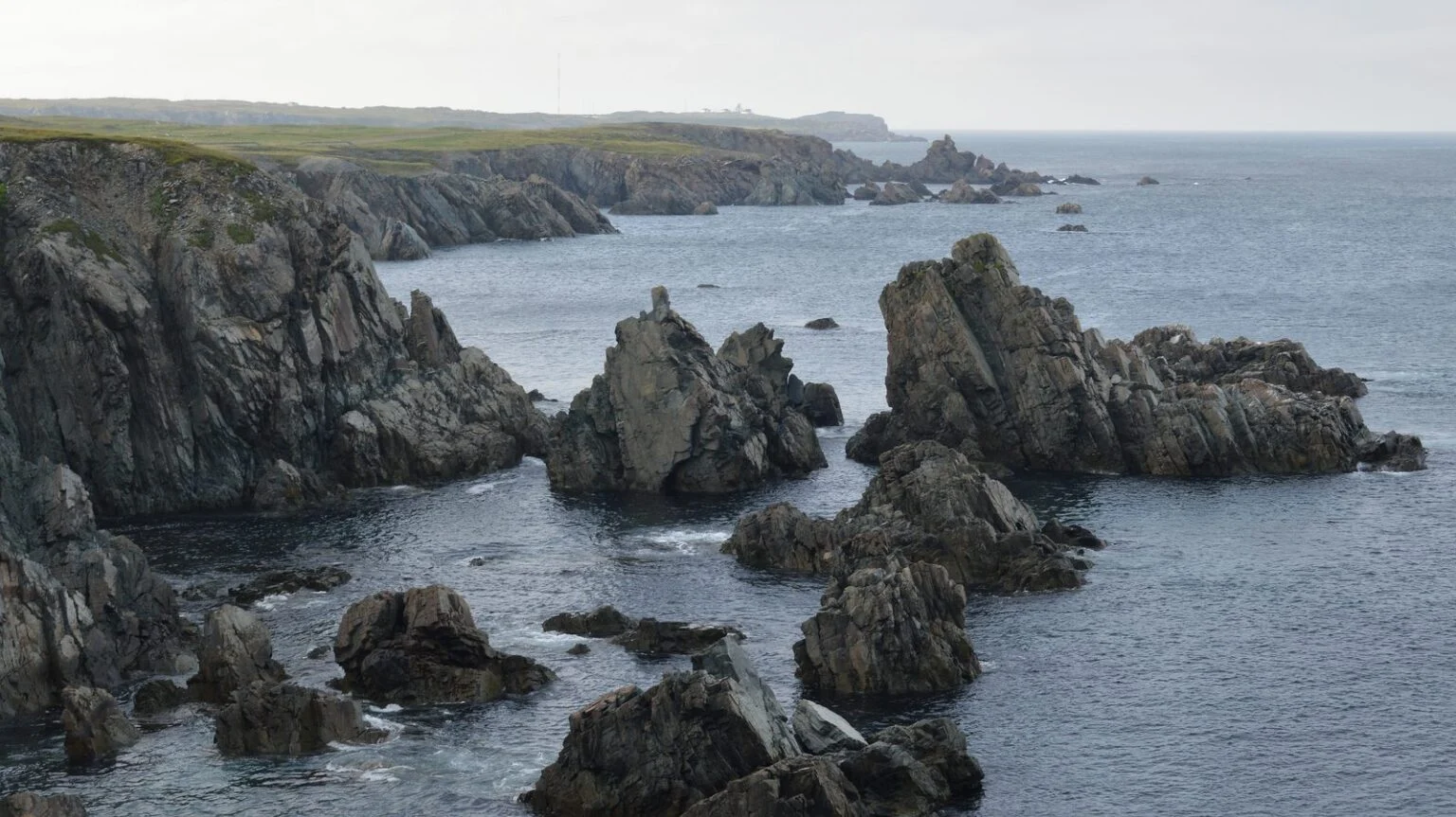 Newfoundland Wind Storm 2026 — Weekend Gusts Knock Out Power Across The Island Rocky cliffs and sea stacks on the Bonavista coast during the Newfoundland Wind Storm weekend, with moody grey skies over the Atlantic