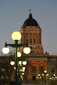 Manitoba Legislature building at dusk as Obby Khan resigns as PC leader