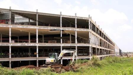 EV battery factory under construction, steel framework and excavator on site