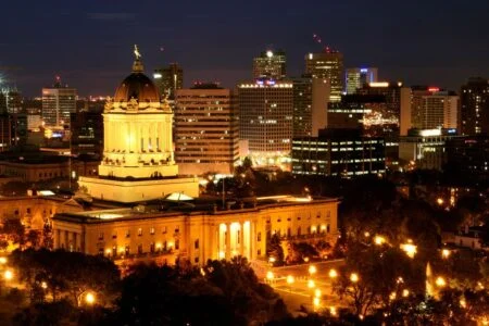 Health Ministers Meeting 2026 — Winnipeg Hosts Provinces As Ottawa Extends $1.2B In Mental Health Funding The Manitoba Legislative Building lit up at night in Winnipeg, host city of the Health Ministers Meeting 2026